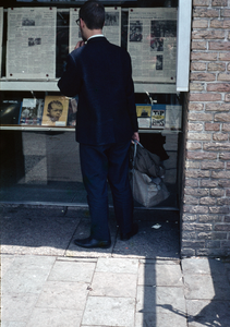 849833 Afbeelding van een man die de krant leest in de vitrines van het kantoor van het Nieuw Utrechts Dagblad ...